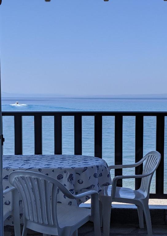 a table and chairs on a balcony with the ocean at Seafront Apartment Pefkochori in Pefkochori