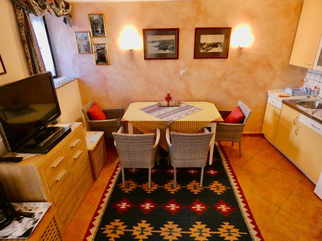 een eetkamer met een tafel en stoelen en een televisie bij Apartments Getruda in Krk