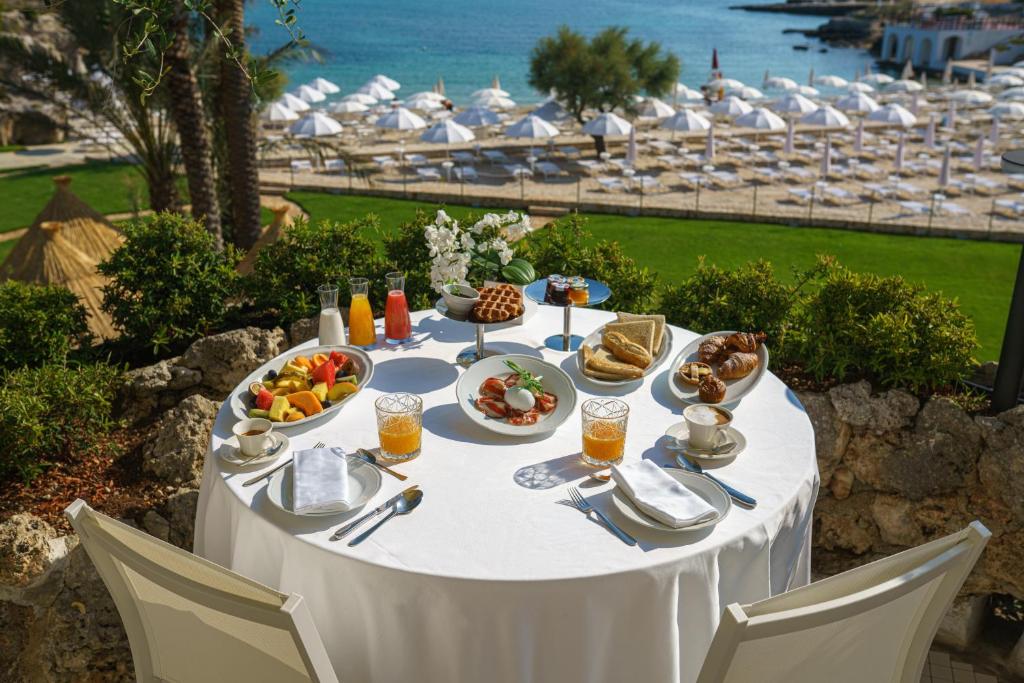 una mesa blanca con comida y vistas al océano en Grotta Palazzese Beach Hotel, en Polignano a Mare