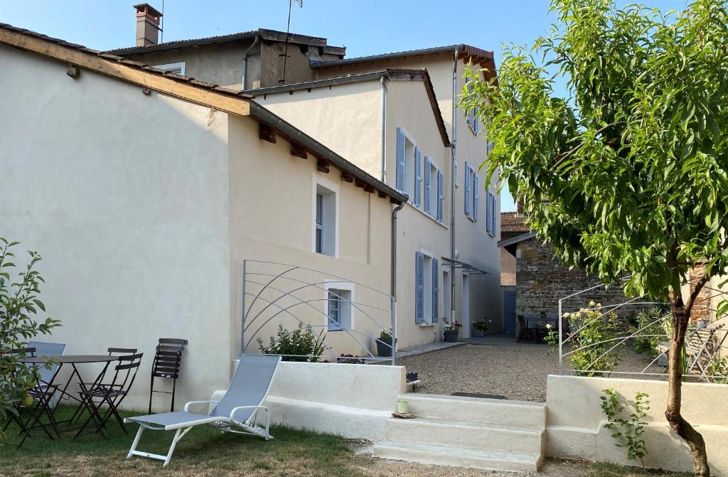 une maison blanche avec une chaise et une table dans l'établissement Aux Portes du Beaujolais, à Belleville-sur-Saône