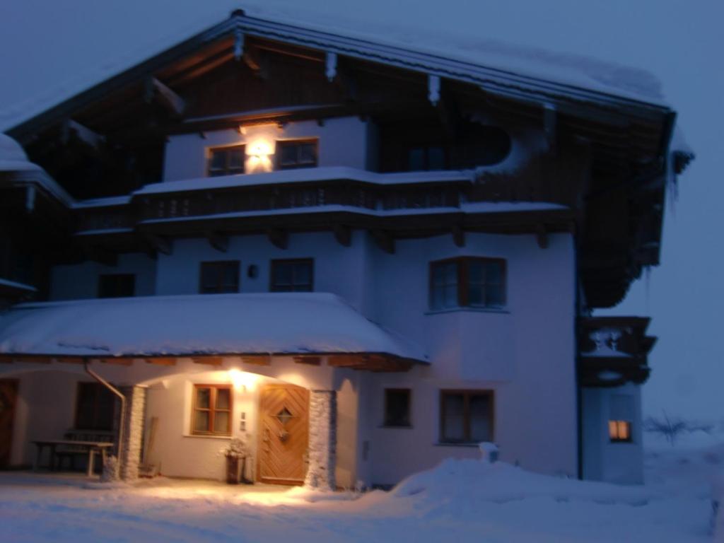 a house with snow on the roof with lights on at Tischlergut in Leogang