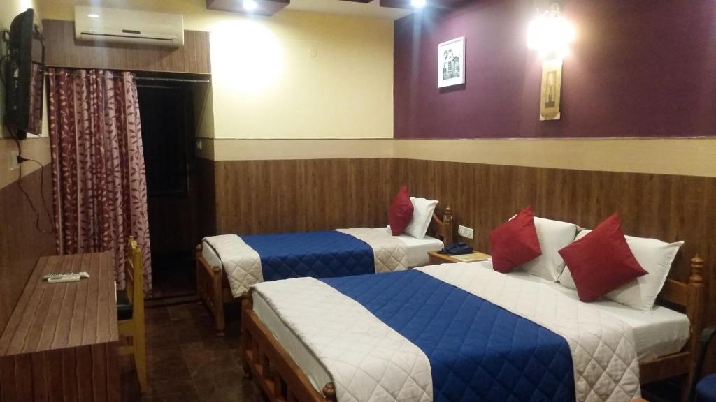 Habitación de hotel con 2 camas y almohadas azules y rojas en Hotel nala residency, en Tiruvannāmalai