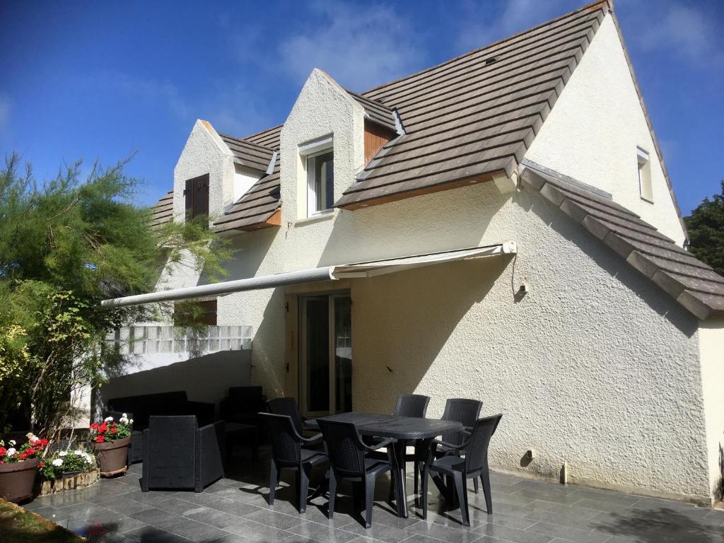 un patio avec une table et des chaises devant une maison dans l'établissement Cottage au pied des dunes, à Le Touquet-Paris-Plage