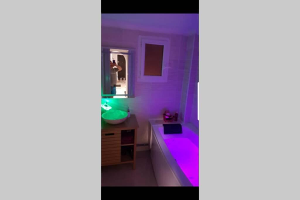 La salle de bains est pourvue d'une baignoire pourpre et d'un lavabo. dans l'établissement Appartement front Vieux Port tout option jacuzzi, à Marseille