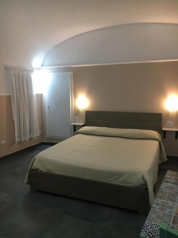 a bedroom with a bed and two lights on the wall at Casa Cortes in Grottaglie