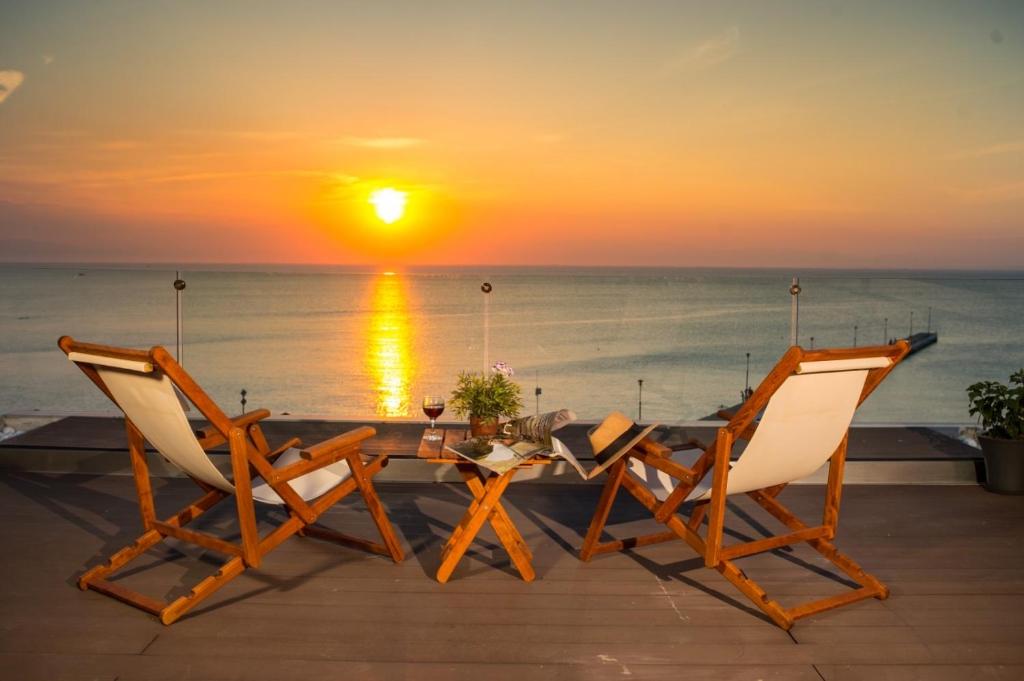 een tafel en twee stoelen met een zonsondergang op de achtergrond bij Peraia Rooms in Perea