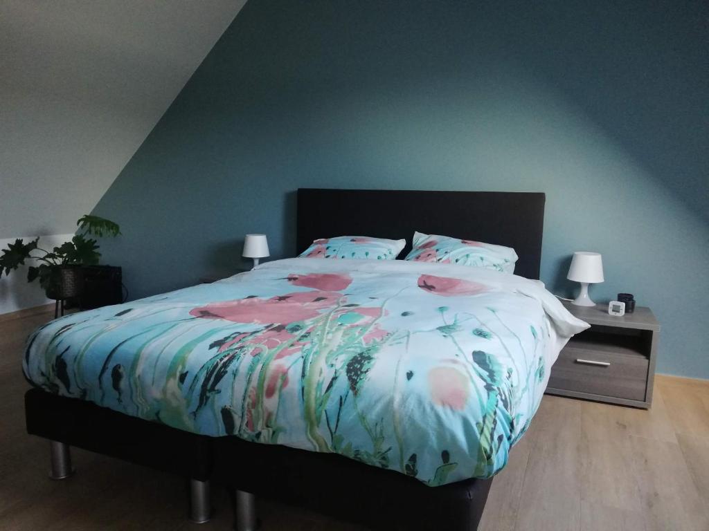 um quarto com uma cama com um edredão floral em B&B Lora em Langemark