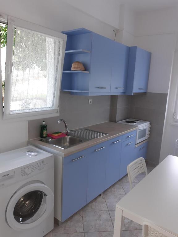 a kitchen with a washing machine and blue cabinets at Falopa Apartments in Parga