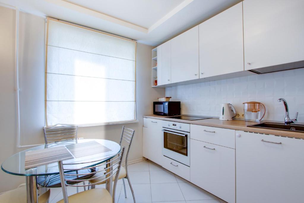 a kitchen with white cabinets and a table with chairs at Аппартаменты на Дзержинского,19 in Khabarovsk