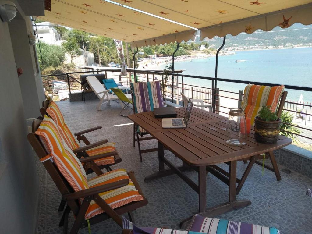een houten tafel en stoelen op een veranda met uitzicht op het water bij Villa Alexandra in Iraklitsa