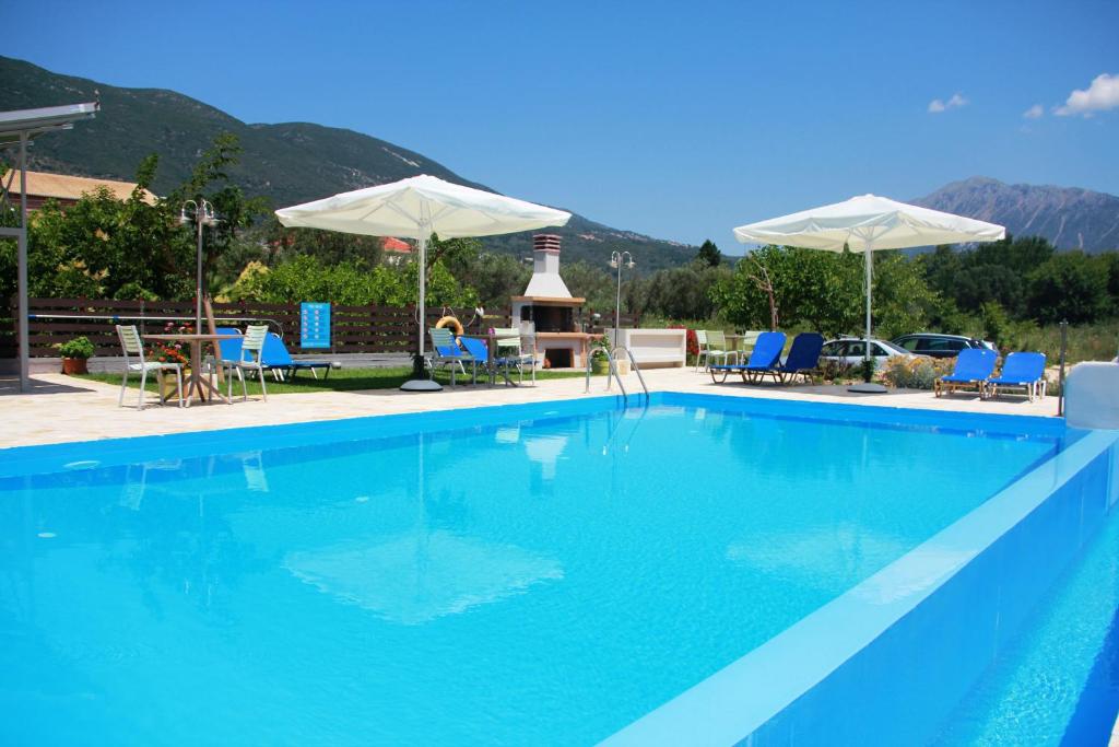 a large blue swimming pool with blue chairs and umbrellas at George Studios in Vasiliki