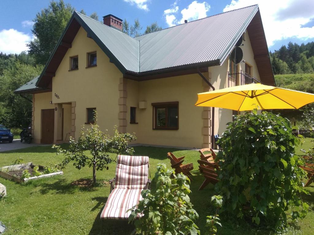a house with two chairs and an umbrella at Apartamenty Grosik in Krynica Zdrój