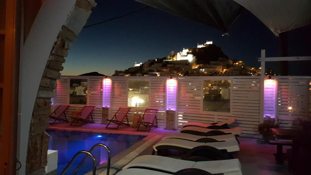 a swimming pool with chairs and a building with a hill at Markos Village Pension in Ios Chora