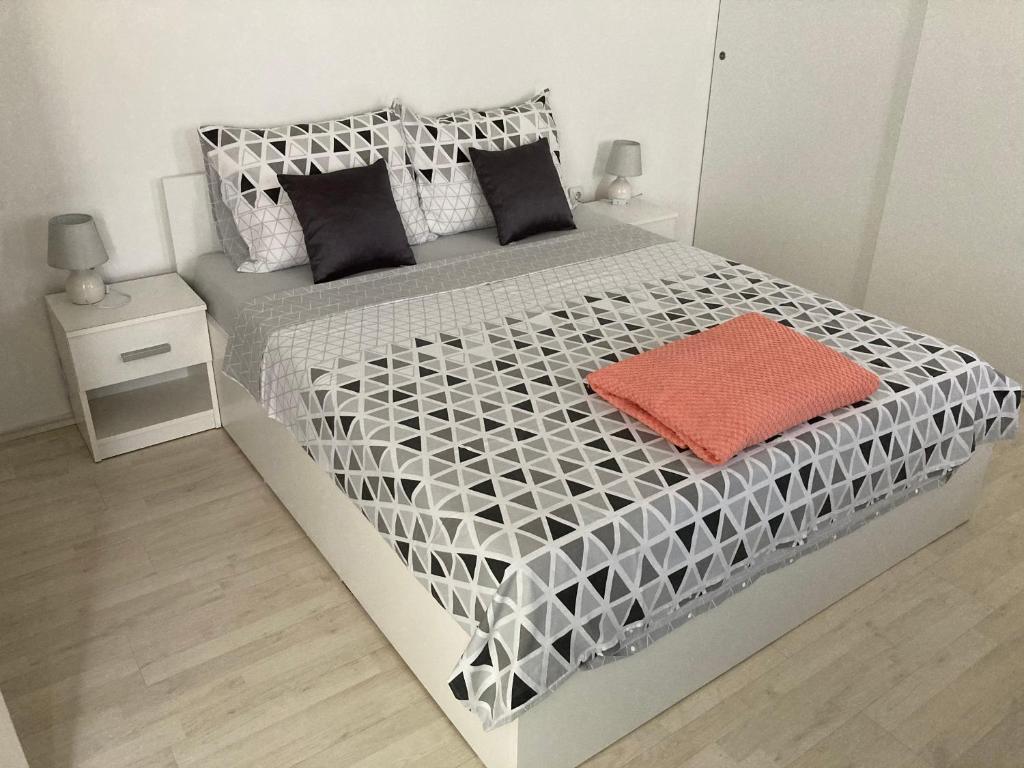 ein Schlafzimmer mit einem weißen und schwarzen Bett mit einem orangefarbenen Kissen in der Unterkunft Studio apartman Valentina in Velika Mlaka