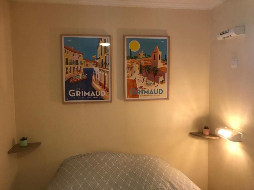 グリモーにあるLES RESTANQUES DE SAINT-TROPEZのベッドルーム1室(壁に2つのポスター付)、ベッド1台が備わります。