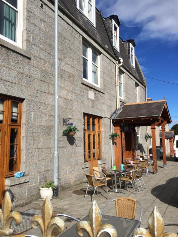 un patio avec des tables et des chaises en face d'un bâtiment dans l'établissement The Banks Of Ury, à Inverurie