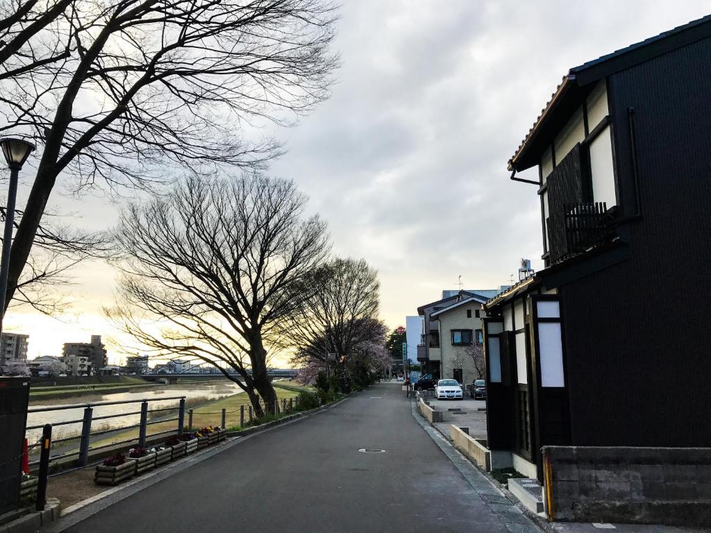 an empty street with trees and a house and a fence at Saigawa House in Kanazawa
