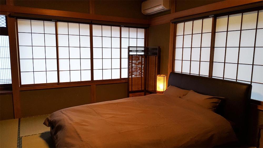 a bedroom with a bed and three windows at Hida House in Takayama