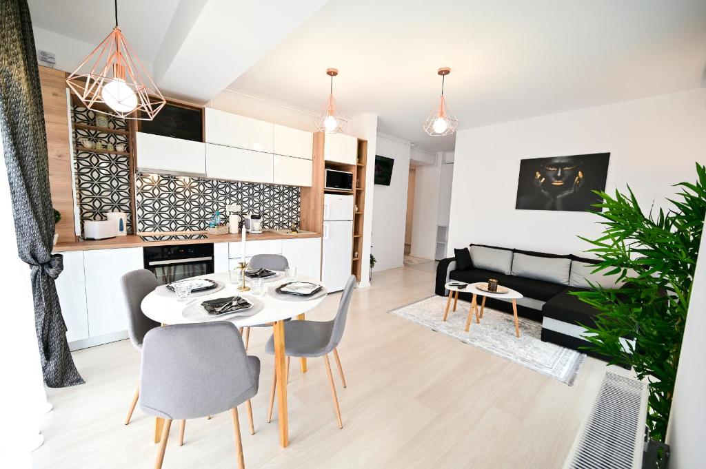 een eetkamer en een woonkamer met een witte tafel en stoelen bij Novus Apartment in Mamaia Nord – Năvodari