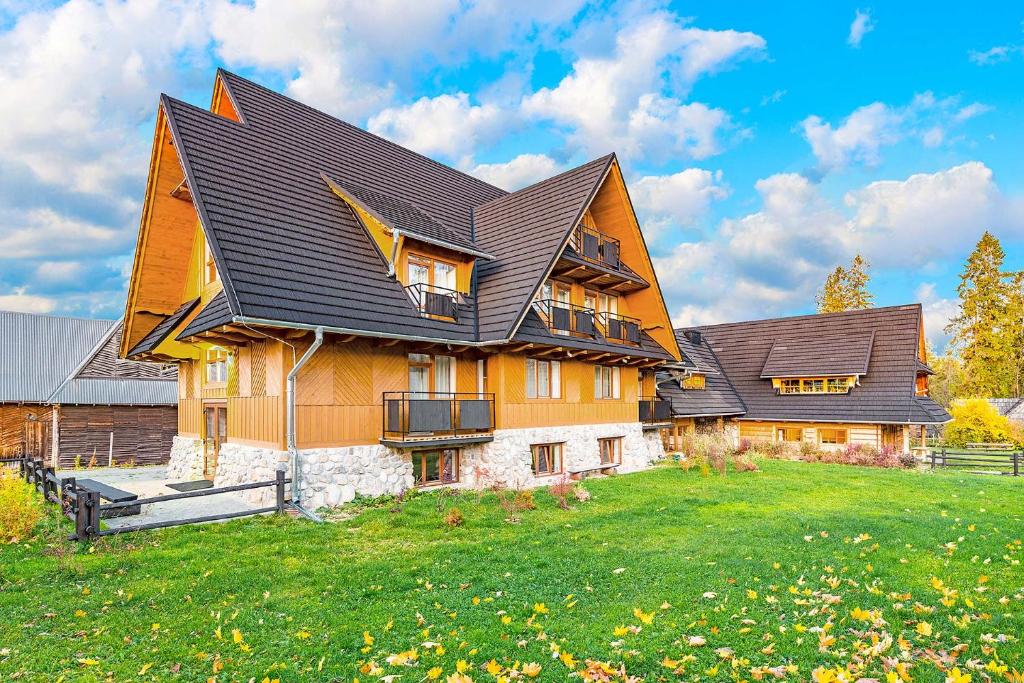 une maison avec un toit en gambrel sur une cour verdoyante dans l'établissement Dom Pod Lasem, à Murzasichle