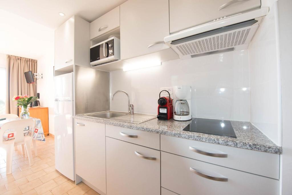 a kitchen with white cabinets and a counter top at Résidence Arinella in Lumio