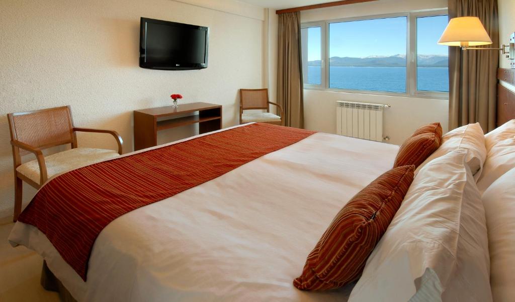a hotel room with a large bed and a window at Hotel Tirol in San Carlos de Bariloche