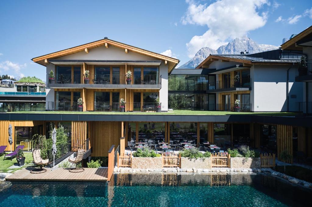 a house with a pool in front of it at Wellness und Brunch Hotel MorgenZeit beheizter Naturteich Genuss Frühstück bis 13 Uhr Hochkönig Sommercard in Maria Alm am Steinernen Meer