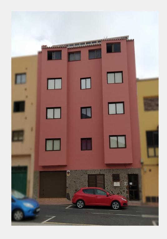 a red car parked in front of a building at apartamentos la villa 3 in San Sebastián de la Gomera