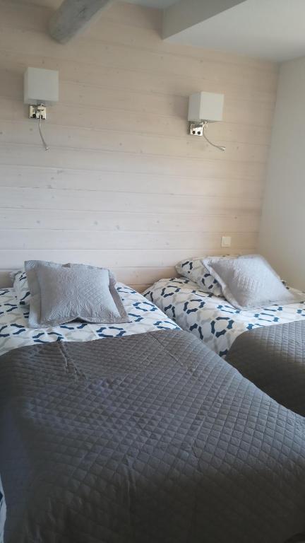 two beds in a bedroom with two lamps on the wall at Gite La Bastide in Ornans