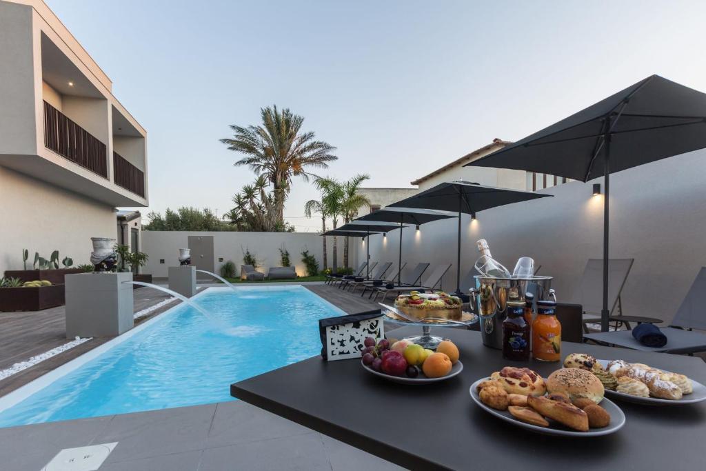 a table with food on it next to a swimming pool at Giafra Luxury Rooms in Agrigento