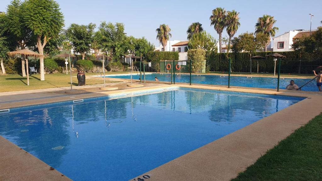 ein großer blauer Pool in einem Park mit Palmen in der Unterkunft Apartamento EL REAL - Espartinas - SEVILLA in Espartinas