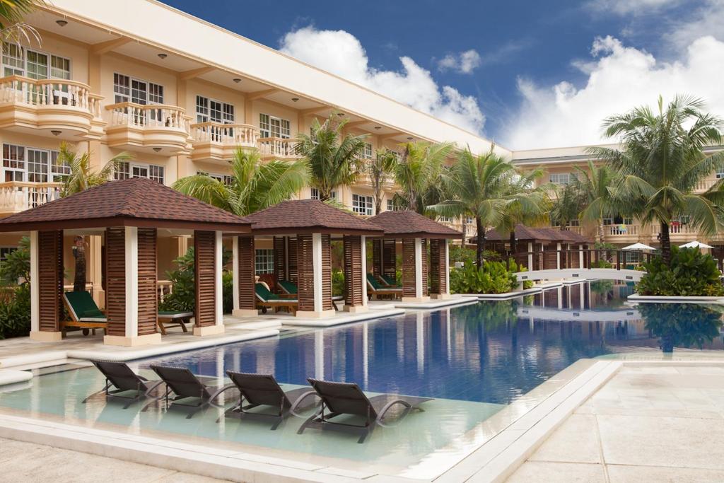 a resort with a swimming pool with chairs and palm trees at Henann Garden Resort in Boracay