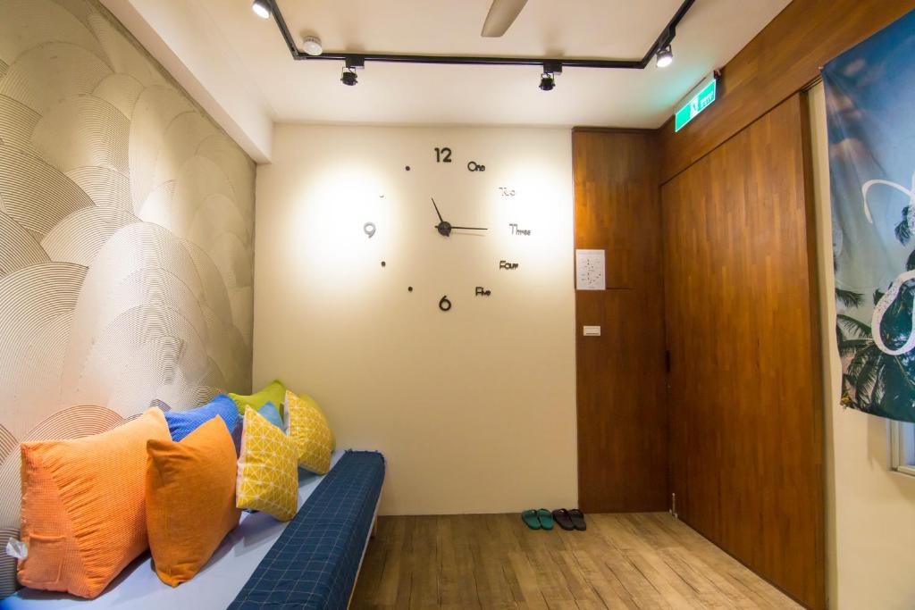 Habitación con sofá y reloj en la pared en One Heart Inn en Tainan