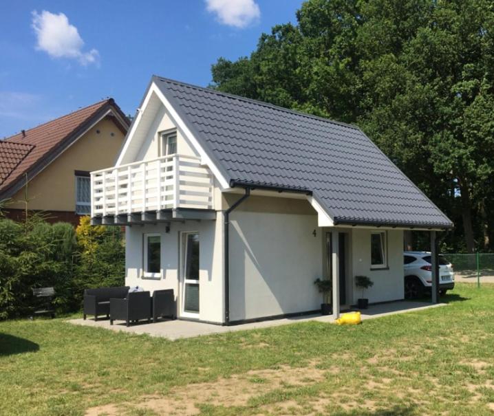 una pequeña casa blanca con techo negro en Domki Letniskowe Stokrotka en Pustkowo