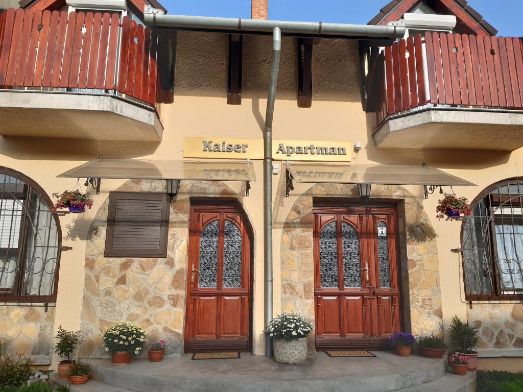 a building with two wooden doors and two balconies at Kaiser Apartman in Hévíz