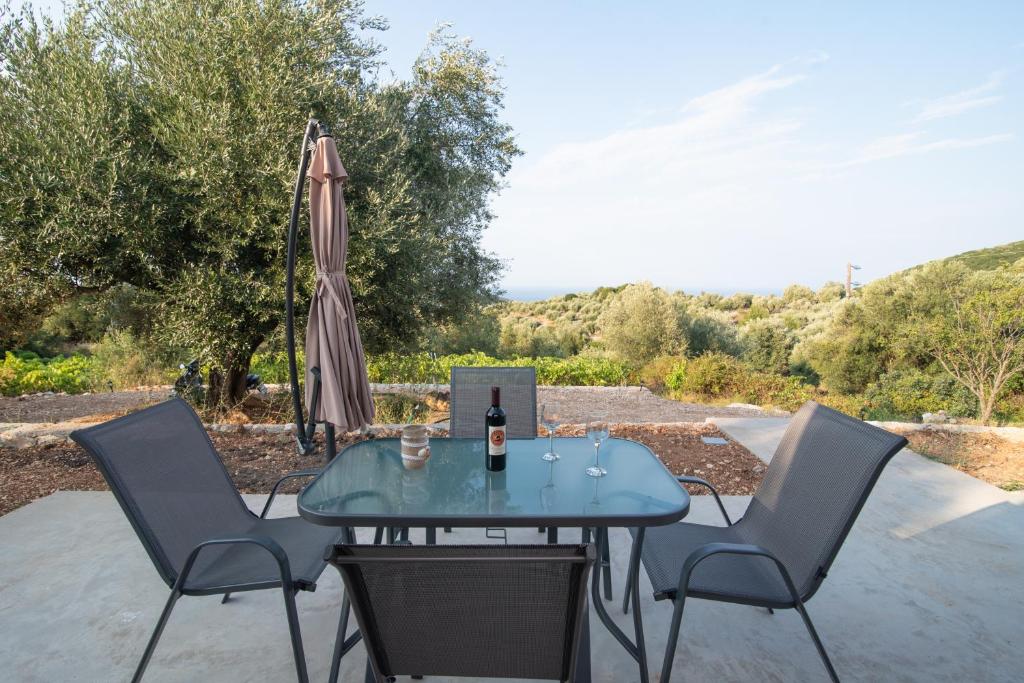 a table and chairs with a bottle of wine and an umbrella at Οίνου Γη Ιθάκη - Winelandithaca in Perakhórion