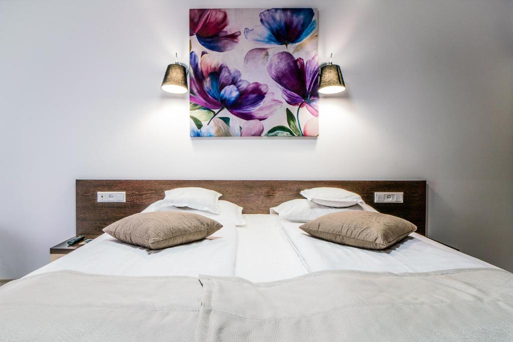 1 cama con 2 almohadas y una pintura en la pared en Hotel Eden, en Câmpulung Moldovenesc