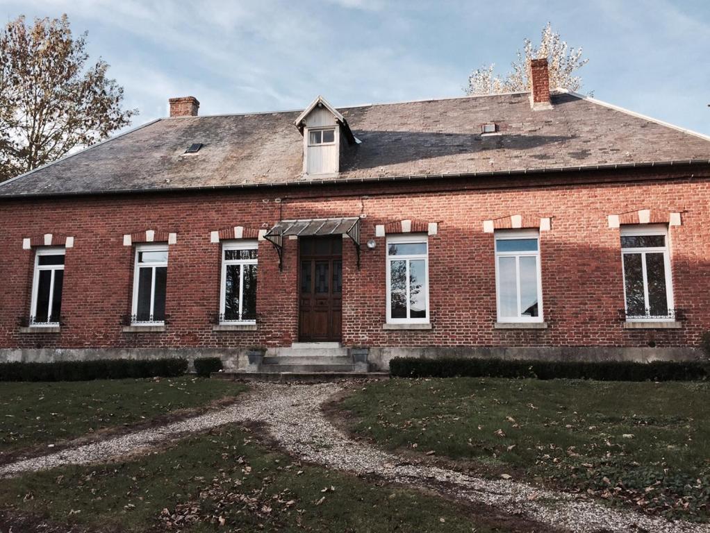 uma velha casa de tijolos vermelhos com uma porta em GrIsa'Home le gîte em Aisonville-et-Bernoville