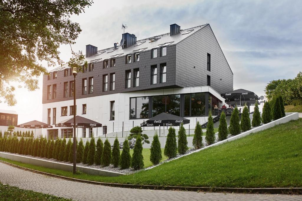 a building with a row of trees in front of it at OKRA RESORT & SPA in Drawsko Pomorskie