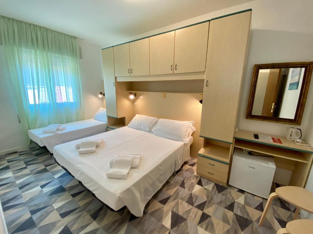 Habitación de hotel con 2 camas y espejo en Giovanna Rooms, en Caorle