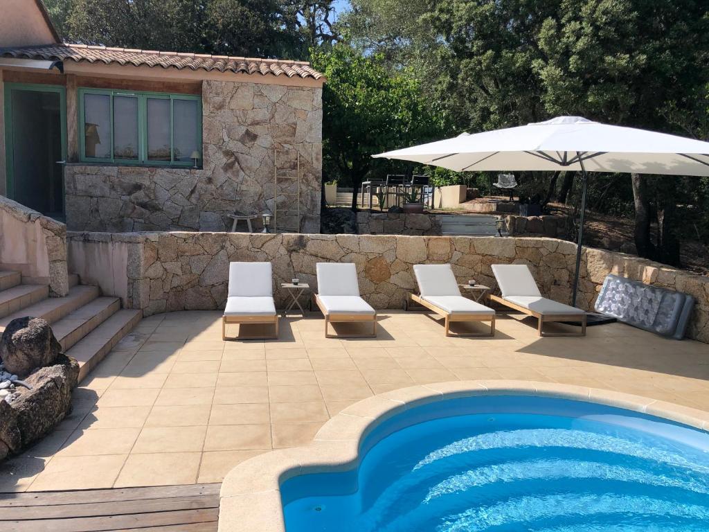 a swimming pool with two chairs and an umbrella at Maison Ferruccio in Porto-Vecchio