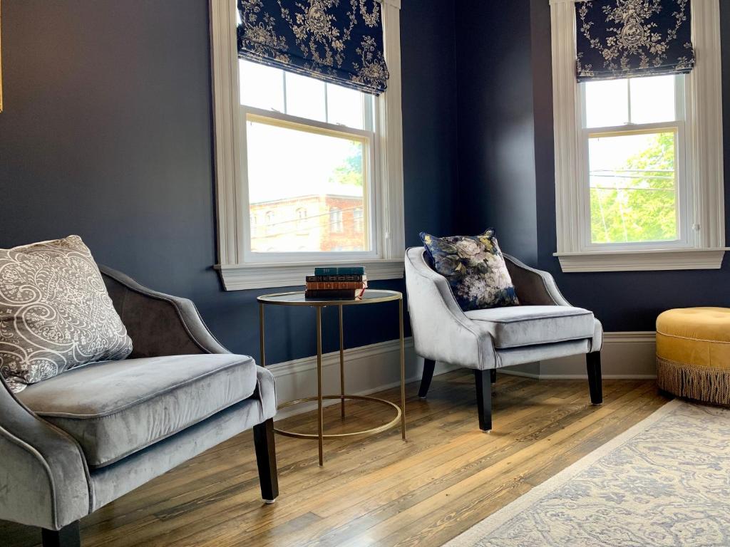 a living room with two chairs and a table and two windows at Slaymaker & Nichols Gastro House & Inn in Charlottetown