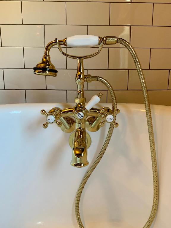 a gold bath tub with a shower head at Slaymaker & Nichols Gastro House & Inn in Charlottetown