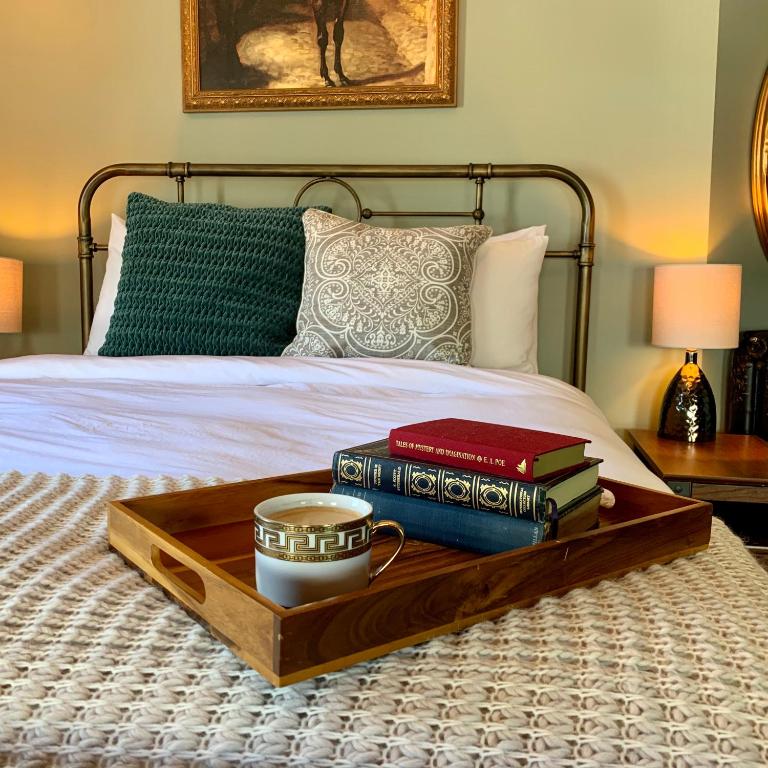 a tray with books and a cup on a bed at Slaymaker & Nichols Gastro House & Inn in Charlottetown