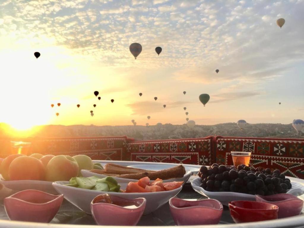 a table topped with bowls of fruit and hot air balloons at Katapa Stone House in Goreme