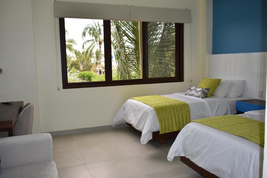 1 dormitorio con 2 camas y ventana en Hotel La Laguna Galapagos, en Puerto Villamil
