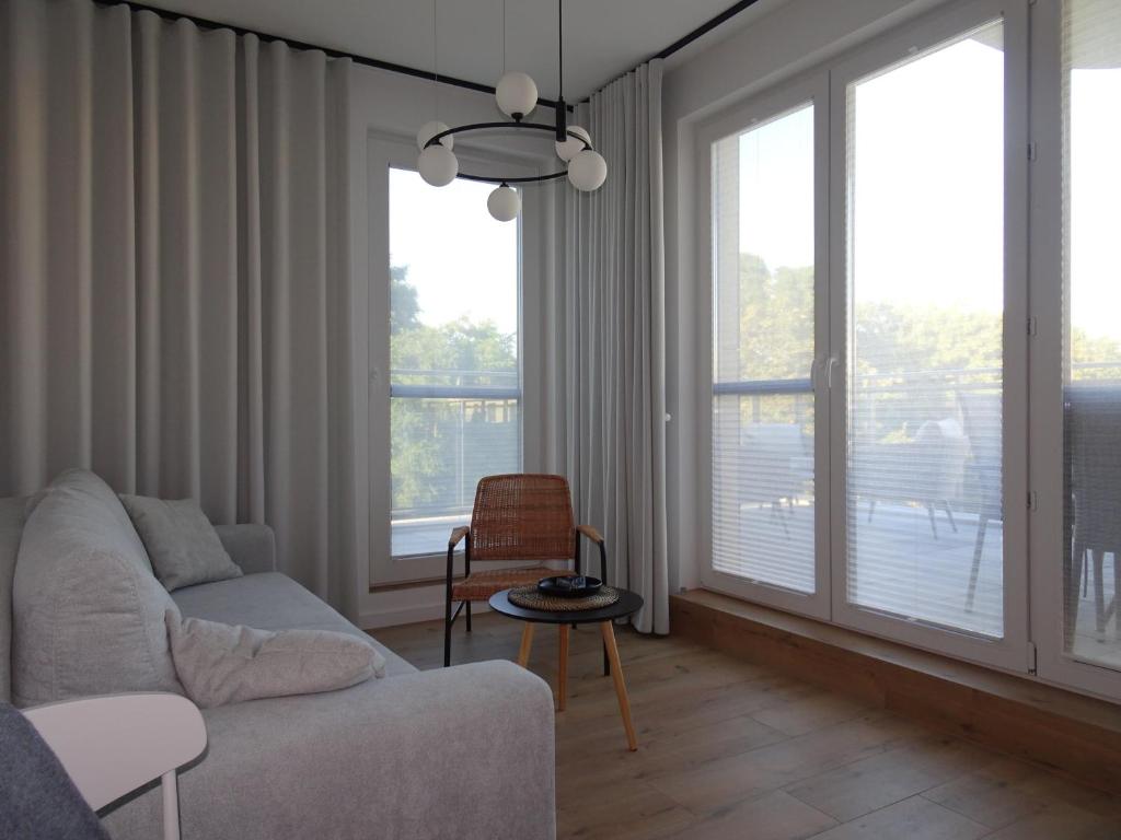 a living room with a couch and two large windows at VIP apartament w parku nad Zatoką in Puck