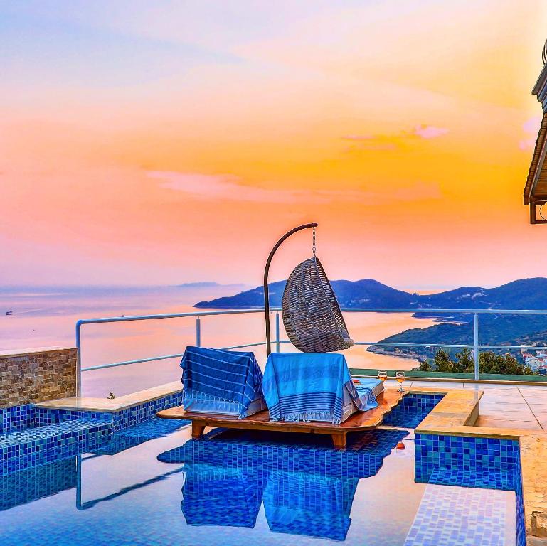 une terrasse avec deux chaises bleues au bord d'une piscine dans l'établissement Sunset Butik Aparts, à Kaş