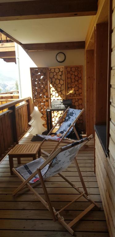 eine Holzterrasse mit einem Tisch und einem Stuhl in der Unterkunft Résidence : Le Crystal Chalet in Les Deux Alpes