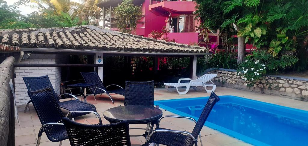 un patio con sillas, una mesa y una piscina en Novos Baianos Hostel e Pousada, en Arraial d'Ajuda